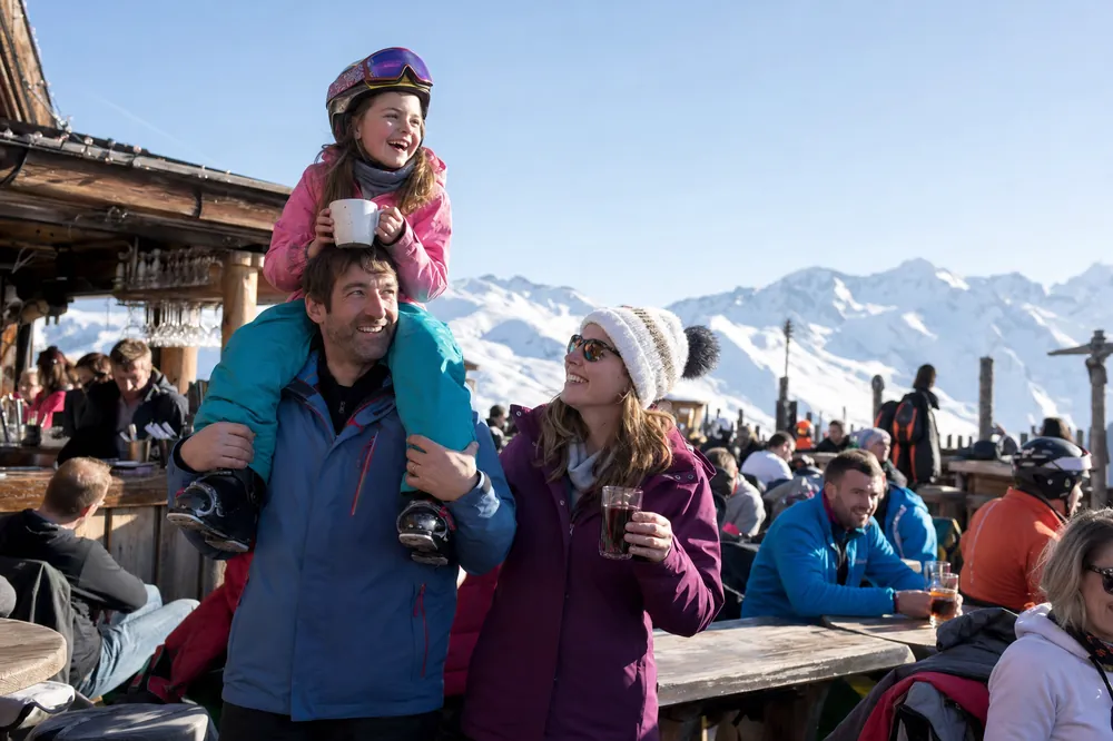 Pappa bærer datteren på skuldrene på en solrik terrasse i Alpene